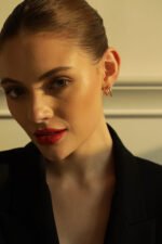 Elegant rose gold hoop earrings on a woman with minimal makeup.