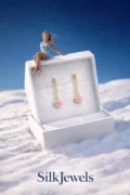 Delicate hanging flower earrings in a jewelry box on snow.