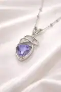Sterling silver necklace with a purple gemstone pendant on satin fabric.