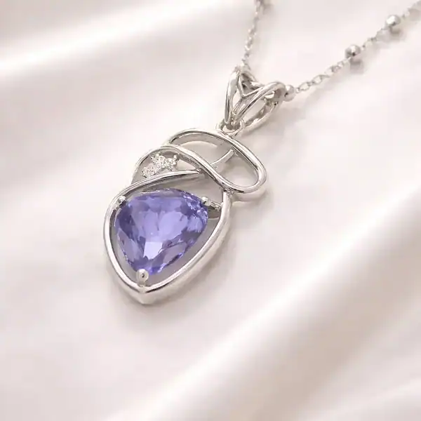 Sterling silver necklace with a purple gemstone pendant on satin fabric.