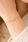 Delicate silver bracelet with heart charm on woman's wrist.