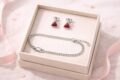 Sterling silver necklace and earrings with red gemstone accents in a jewelry box.