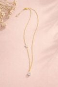 Gold necklace with a sparkling pendant on a pink background.