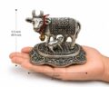 Small metallic cow figurine with intricate designs on a hand.