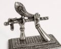 Silver-toned Krishna flute sculpture with detailed hands and base.