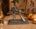 Silver sculpture of Krishna's hands holding a flute on a decorative base.