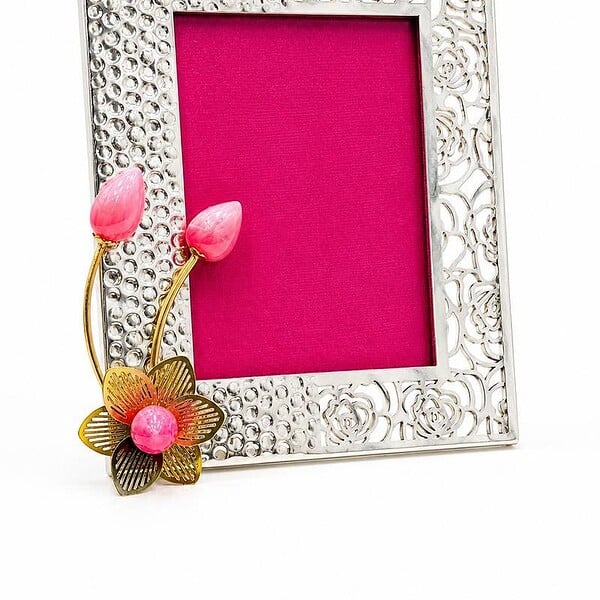 Decorative silver photo frame with pink floral accents and pink background.