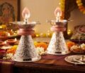 Silver-colored diya oil lamps with pink accents for religious ceremonies.