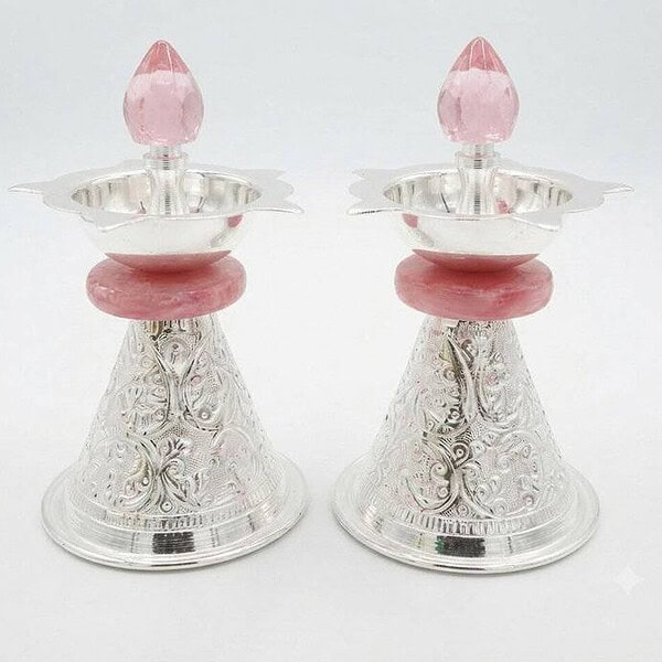 Pair of silver oil lamps with pink accents and intricate designs.