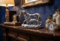 Decorative silver horse and foal figurine on wooden table with vases and lamp.