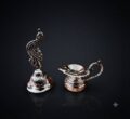 Elegant silver peacock bell and diya for traditional decor.
