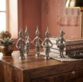 Six silver tribal musician figurines with traditional instruments on wooden surface.