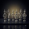 Set of seven silver tribal figurines with intricate details and pointed hats.