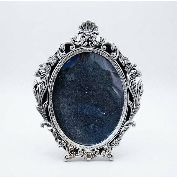 Vintage silver ornate picture frame with dark background.