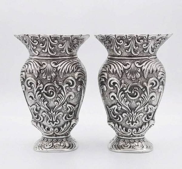 Pair of intricately designed silver vases with ornate patterns.