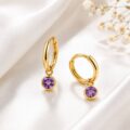 Gold hoop earrings with purple gemstone charms on white fabric background.