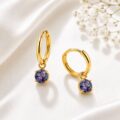 Gold hoop earrings with blue gemstones on a satin background.