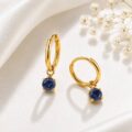 Gold hoop earrings with blue gemstones on a soft fabric background.
