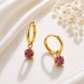 Gold hoop earrings with pink gemstone charms on a satin background.