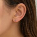 Close-up of a woman's ear with a small purple birthstone stud earring.