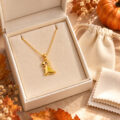 Gold dinosaur pendant necklace in jewelry box with autumn decor.