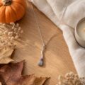 Silver broomstick pendant necklace with purple enamel, autumn flat lay