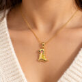 Gold dinosaur pendant necklace with pink and yellow accents on a woman's neck.